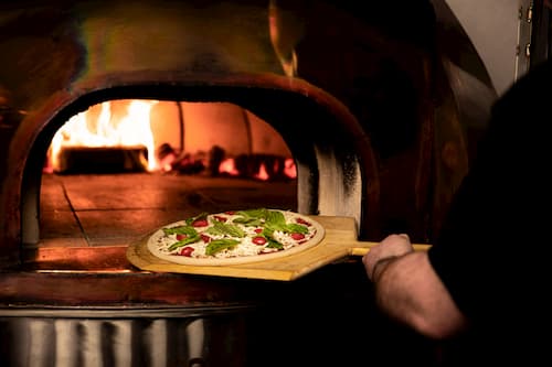 Pizza on a peel going into a wood fired oven