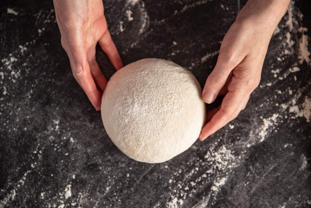 pizza crust dough ball being prepped with flour