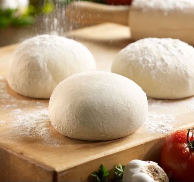 rising pizza dough ball dusted with flour