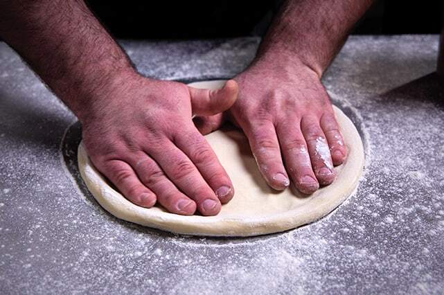 spreading pizza dough and flour