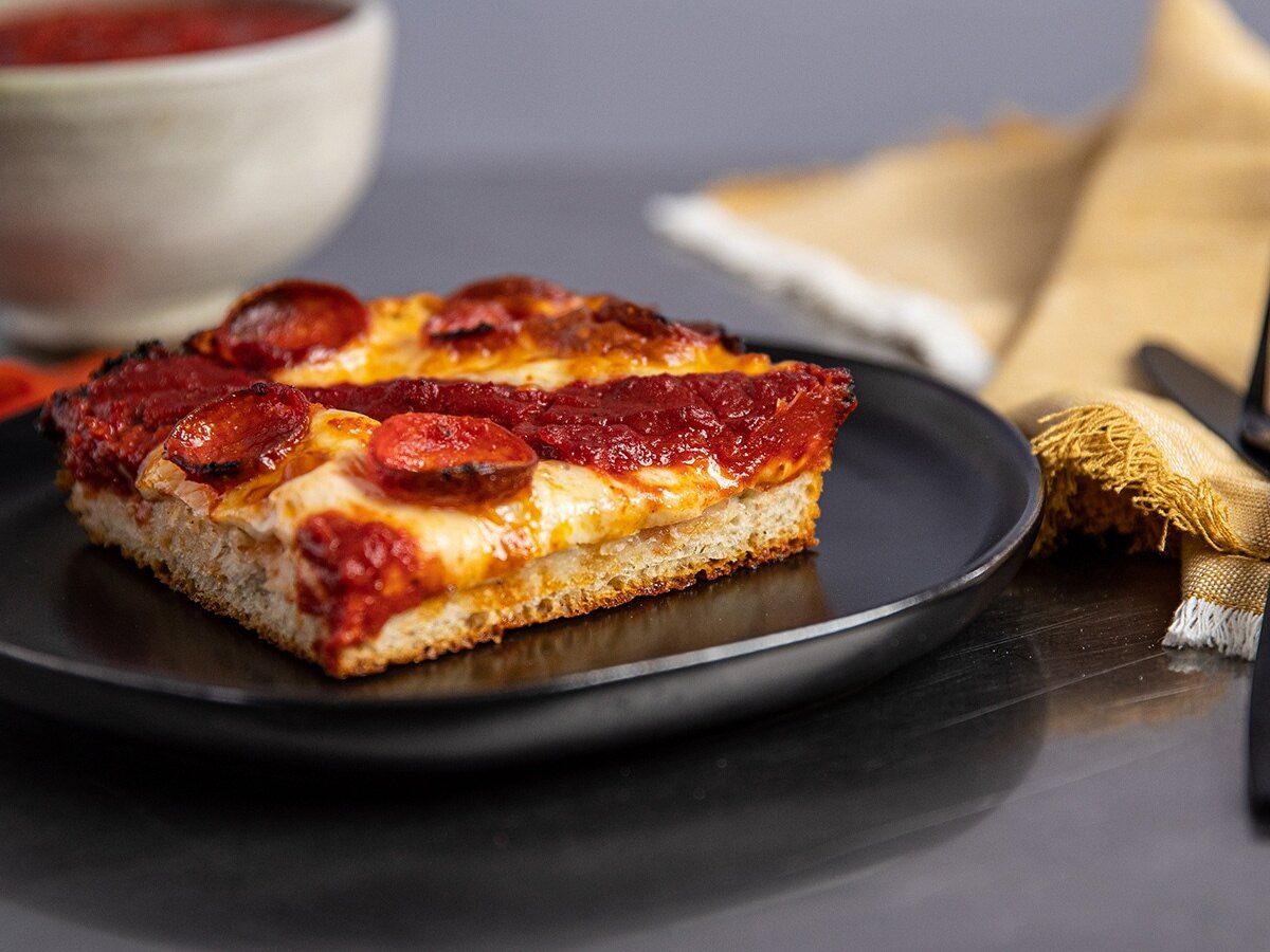 Detroit style pizza on a black plate